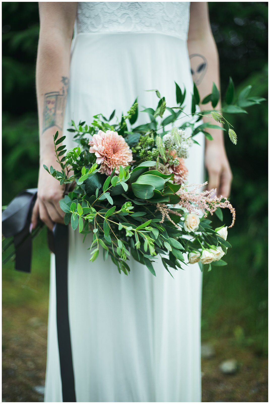 Wild Green and pastel orangey pink flowers in a wedding bouquet tied with grey ribbon 