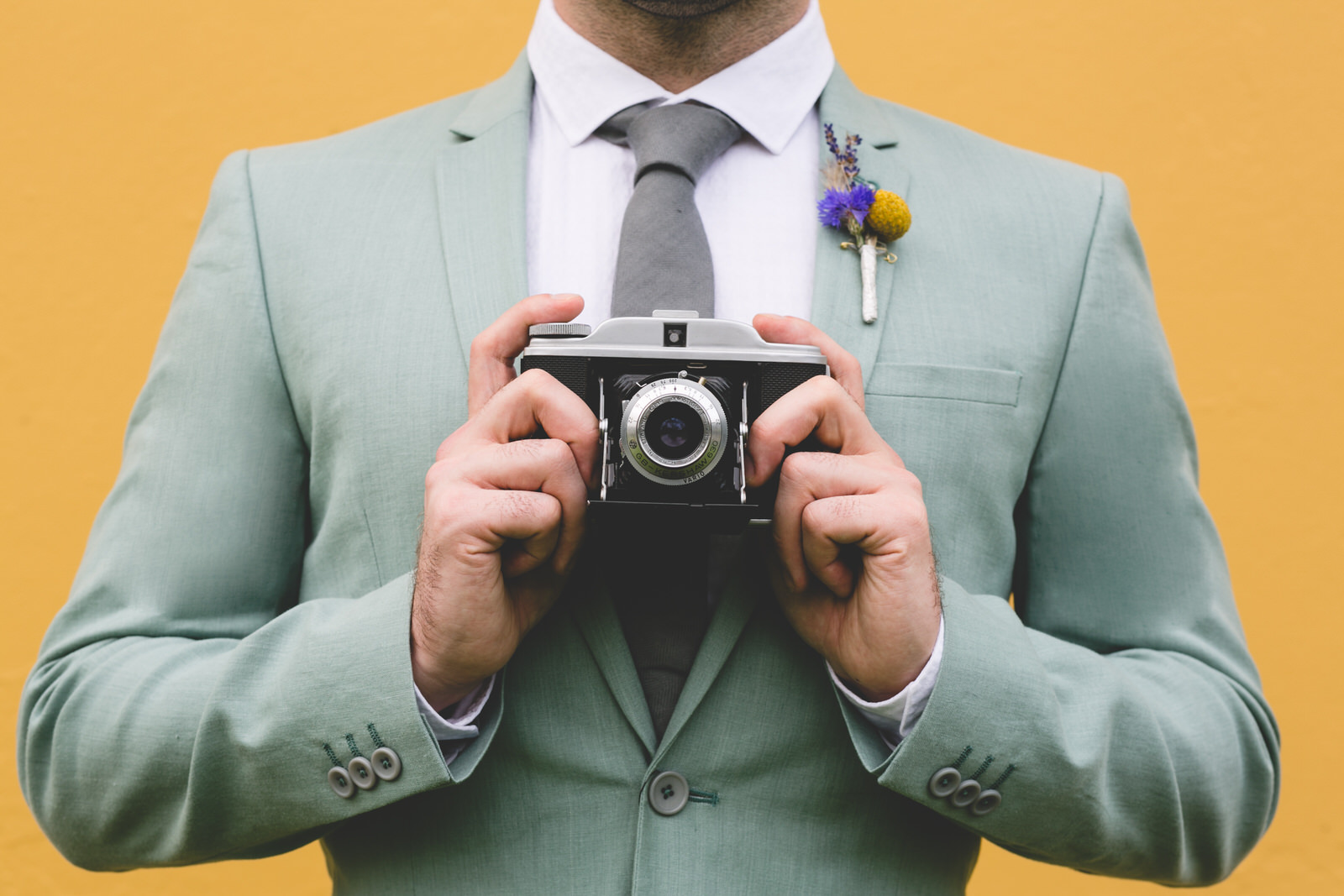 Groom holding a vintage camera